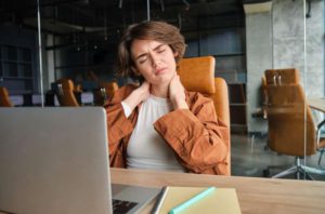 Image of woman with tired face sits with laptop in office feels tension in neck pain