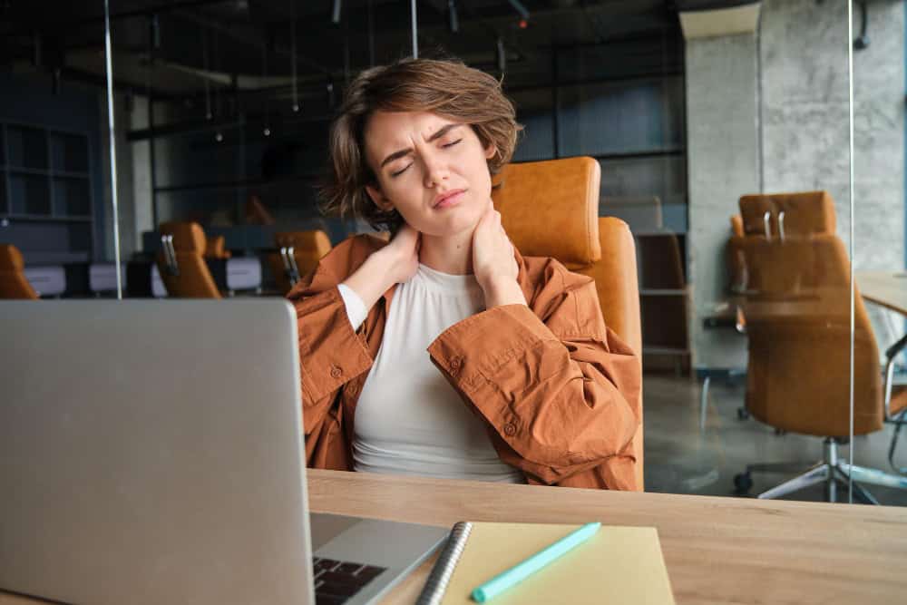 Image of woman with tired face sits with laptop in office feels tension in neck pain