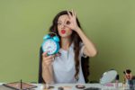 woman with makeup on and holding a clock